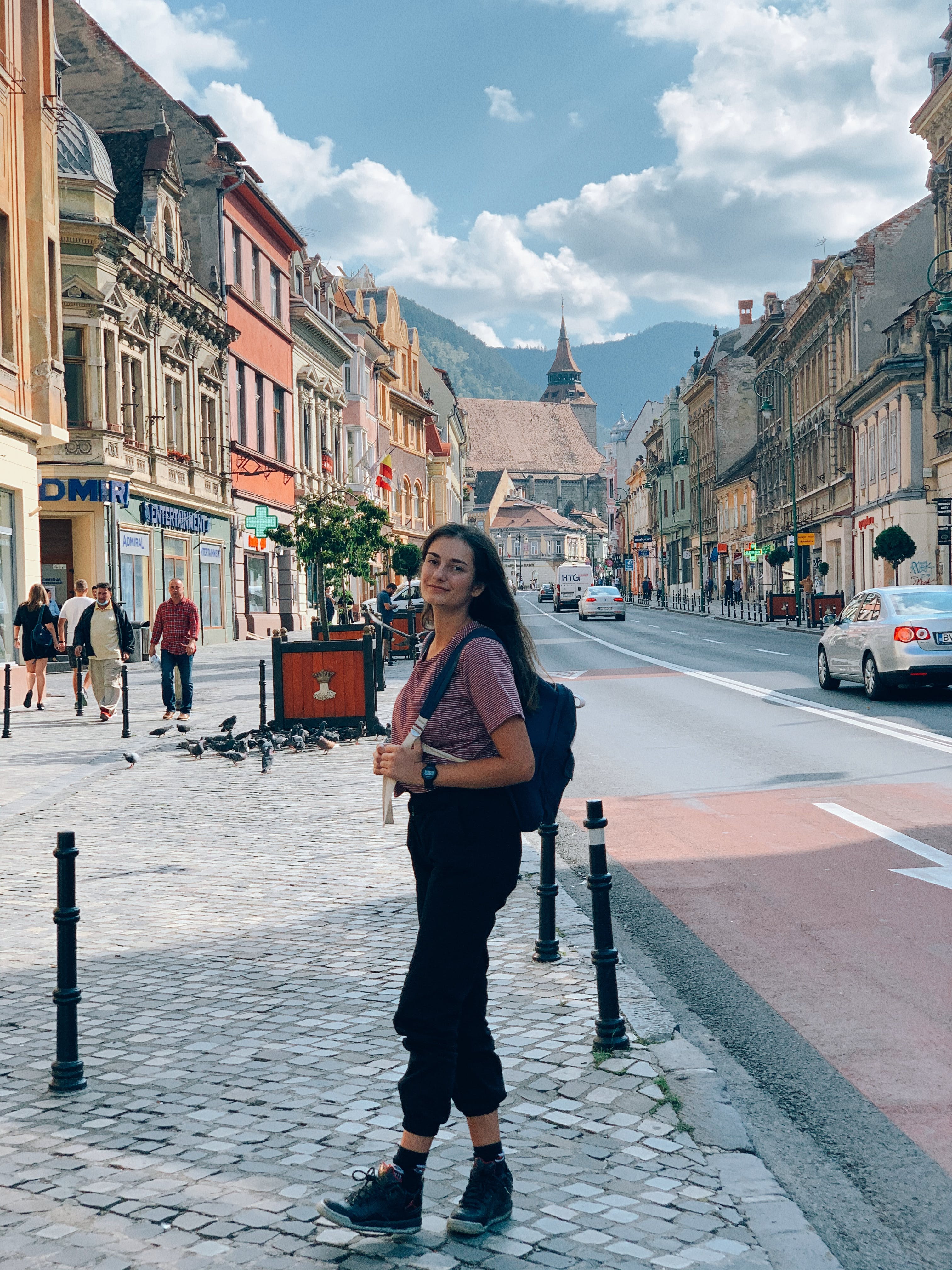 Young female tourist walking in old city during excursion on sunny day