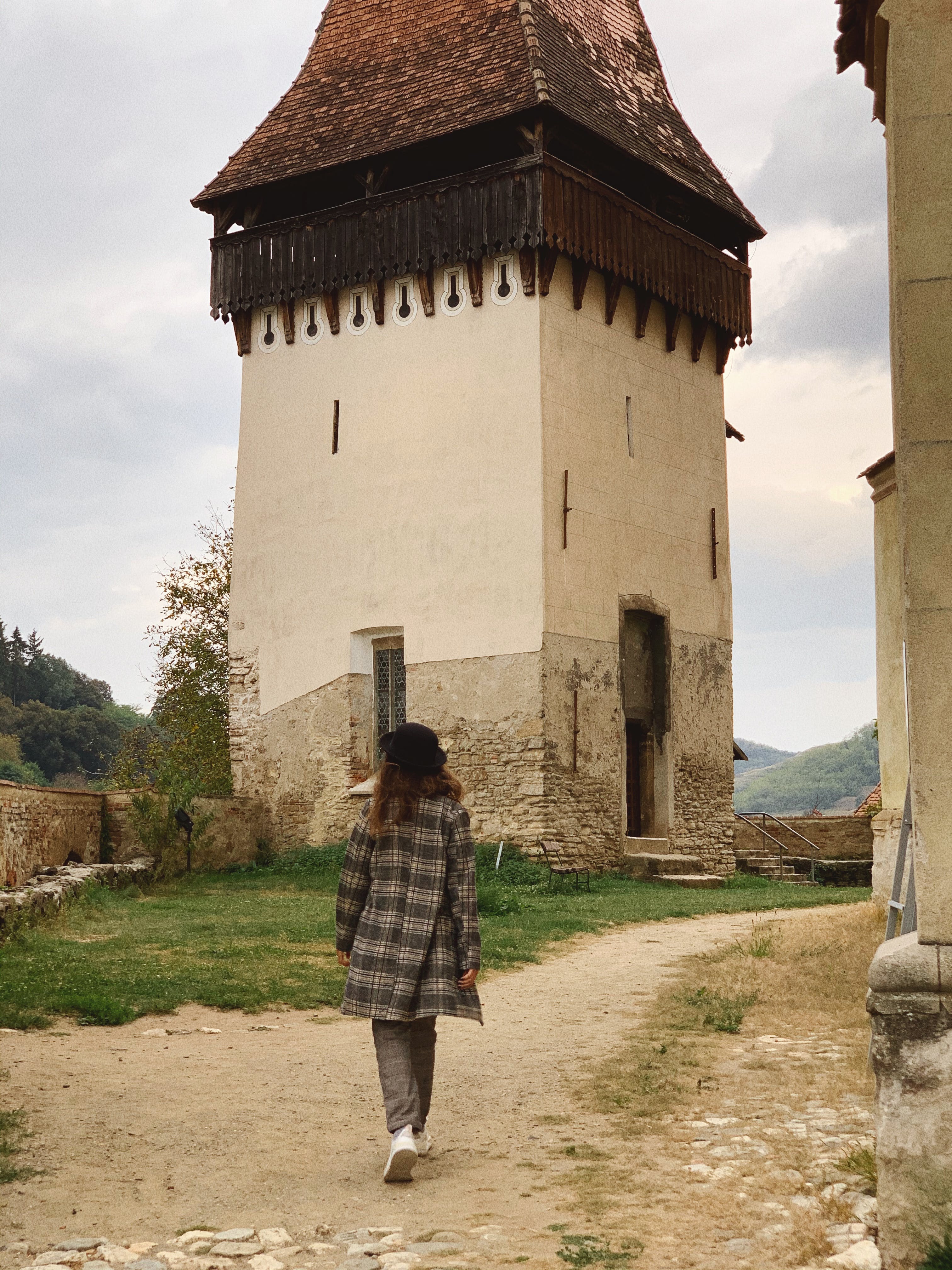 Unrecognizable female traveler walking in village near aged Lutheran fortified church